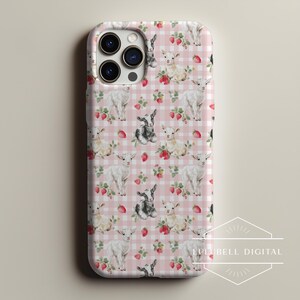 May include: A phone case featuring a repeating pattern of white and black goats, strawberries, and green leaves on a pink gingham background. The case has a triple-lens camera cutout.