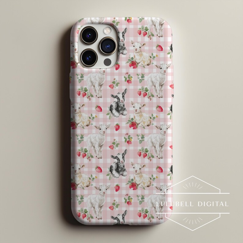May include: A phone case featuring a repeating pattern of white and black goats, strawberries, and green leaves on a pink gingham background. The case has a triple-lens camera cutout.