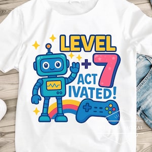 May include: White t-shirt featuring a blue robot graphic with the text "LEVEL 7 ACTIVATED!" and a blue game controller. The design includes a rainbow and yellow star accents, perfect for a birthday.