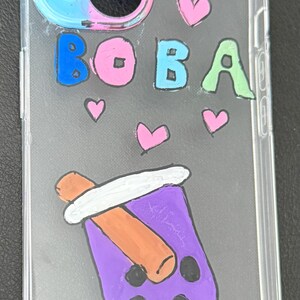 Puede incluir: Funda transparente para tel&eacute;fono con un dise&ntilde;o colorido. La funda presenta la palabra "BOBA" en letras azules, rosas y verdes, junto con corazones rosas y una ilustraci&oacute;n de t&eacute; boba morado. La funda est&aacute; dise&ntilde;ada para un tel&eacute;fono.