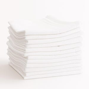 May include: A stack of folded white towels, neatly arranged on a white surface. The towels are crisp and clean, with visible folds and a soft texture. The image is well-lit, highlighting the pristine white color of the towels.