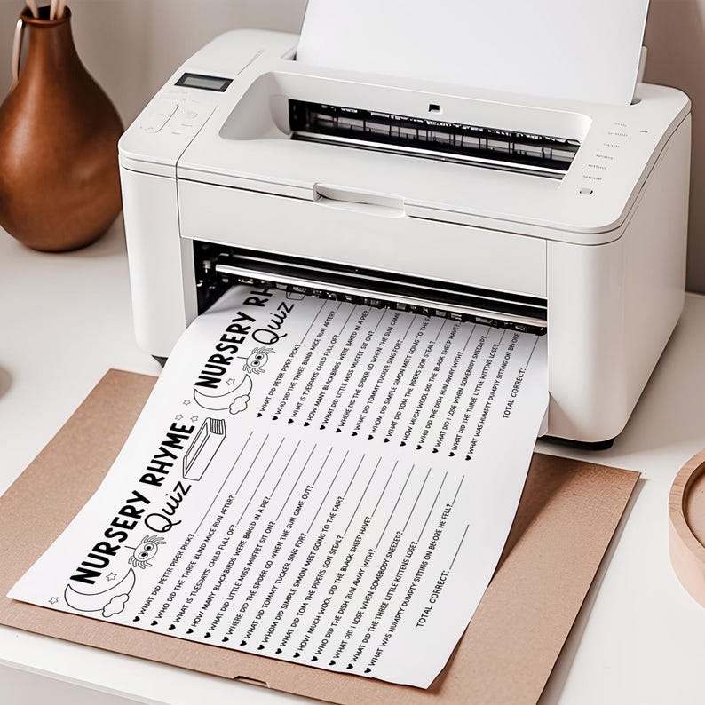 May include: A white printer is printing a black and white nursery rhyme quiz on a sheet of paper. The quiz sheet is on top of a brown paper envelope. The quiz includes questions about nursery rhymes.