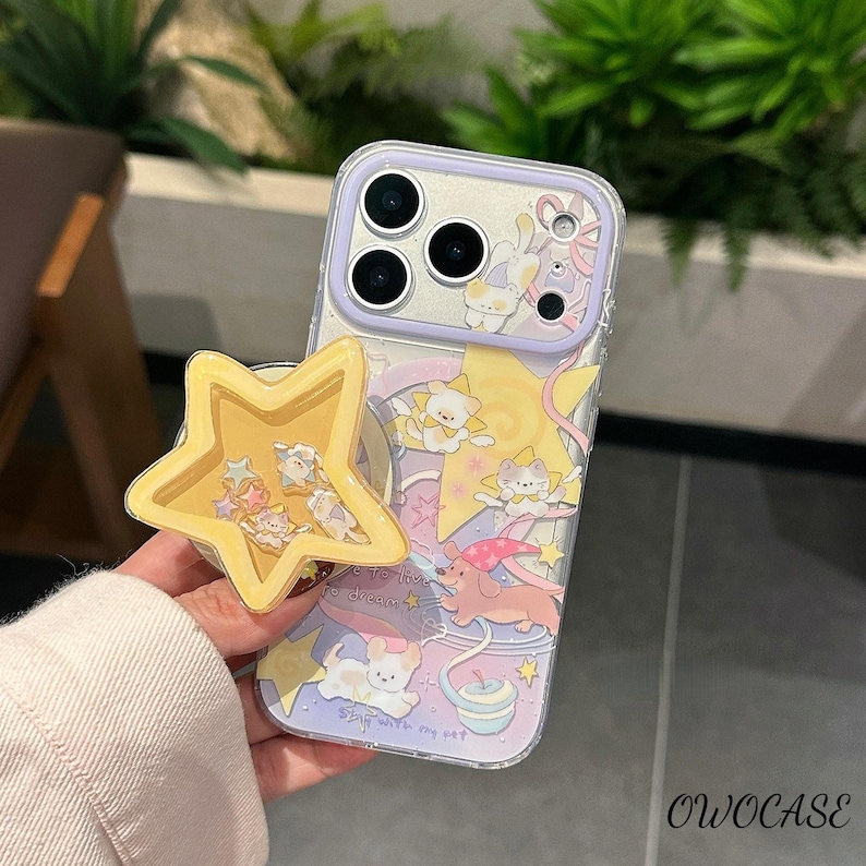 May include: A clear phone case with a cute design of cartoon animals, stars, and pastel colours. A yellow star-shaped phone grip is attached. The case has the text "Stay with my pet" and "Live to dream".