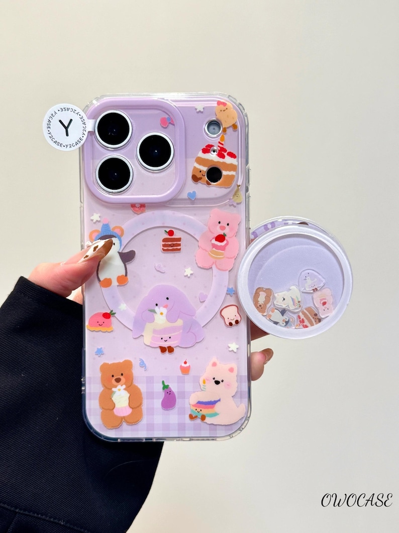 May include: A clear phone case with a purple backing featuring cartoon characters and food designs. The case has a clear, round, floating charm compartment. The case has the text "OWOCASE".