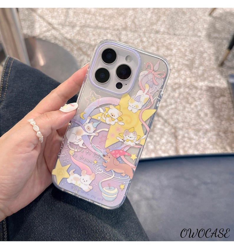 May include: Transparent phone case with a playful design of cartoon cats, stars, and a rainbow. The case has a lilac border and the text "love to live, to dream". The case is designed for a smartphone.