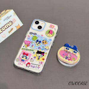 May include: Clear phone case with colorful cartoon character stickers. A matching pop socket is next to the phone. The stickers include a variety of cute characters, stars, and Japanese text. The case has a blue border.
