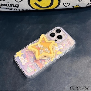 May include: A clear phone case with a colourful cartoon design and a yellow star-shaped phone grip. The case features a whimsical illustration with pastel colours and the text "dream". The phone case is designed to protect the phone while adding a decorative touch.