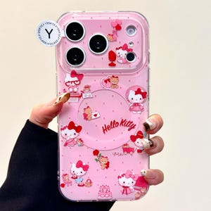Pu&ograve; includere: Custodia per telefono rosa con Hello Kitty e altri personaggi dei cartoni animati. La custodia ha un bordo trasparente e uno sfondo rosa con molteplici illustrazioni di Hello Kitty, cuori e fiocchi. Il testo "Hello Kitty" &egrave; stampato sulla custodia.