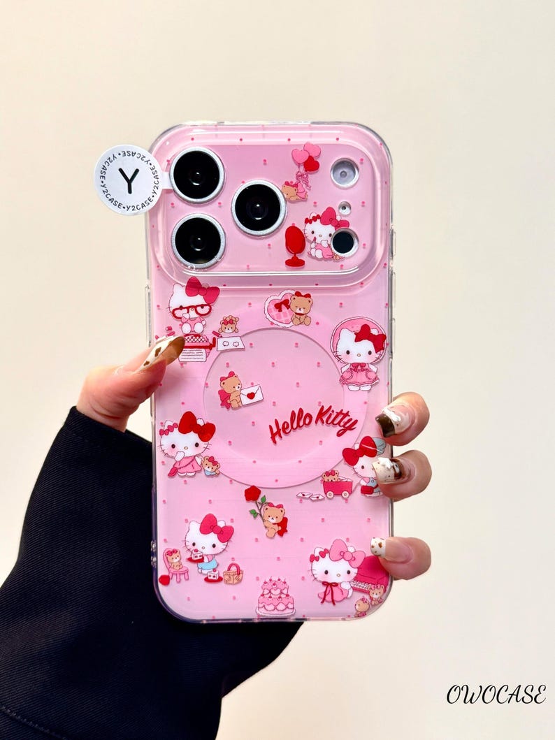Pu&ograve; includere: Custodia per telefono rosa con Hello Kitty e altri personaggi dei cartoni animati. La custodia ha un bordo trasparente e uno sfondo rosa con molteplici illustrazioni di Hello Kitty, cuori e fiocchi. Il testo "Hello Kitty" &egrave; stampato sulla custodia.