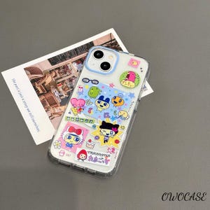 May include: Clear phone case decorated with colorful cartoon stickers. The stickers feature various characters and Japanese text. The case has a light blue border and is on a gray surface. The text "OWOCASE" is visible.
