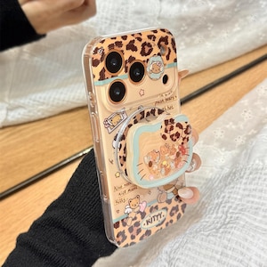 May include: A clear phone case with a leopard print design and a pop-up grip. The case features illustrations of bears and the word "KITTY." The text "Also need nice music Kitty" is also visible. The case is held by a person.