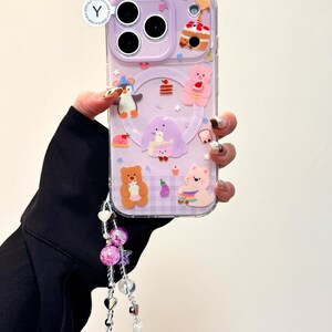 May include: A clear phone case with a lavender background and cartoon bear, penguin, and cake designs. The case has a decorative strap with pink and clear beads. The text "OWOCASE" is visible.