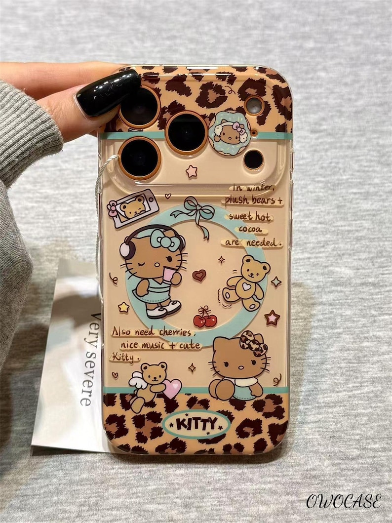 May include: A clear phone case with a leopard print design and illustrations of Hello Kitty and teddy bears. The case features text that reads "In winter, plush bears + sweet hot cocoa are needed." and "Also need cherries, nice music + cute Kitty."