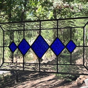 May include: A stained glass window with a rectangular frame and a design of five blue diamond shapes.