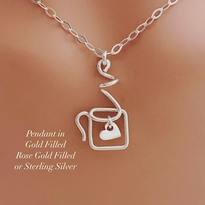May include: A silver necklace with a coffee cup pendant and a small heart charm. The pendant is made of wire and has a steam curl coming from the top. The necklace is available in gold filled, rose gold filled, or sterling silver.