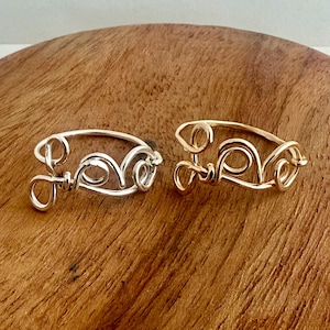 May include: Two wire bracelets, one silver and one gold, with the word "love" spelled out in wire.
