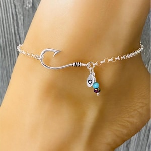 May include: Silver anklet with a fish hook charm, a heart charm, and turquoise and purple beads.