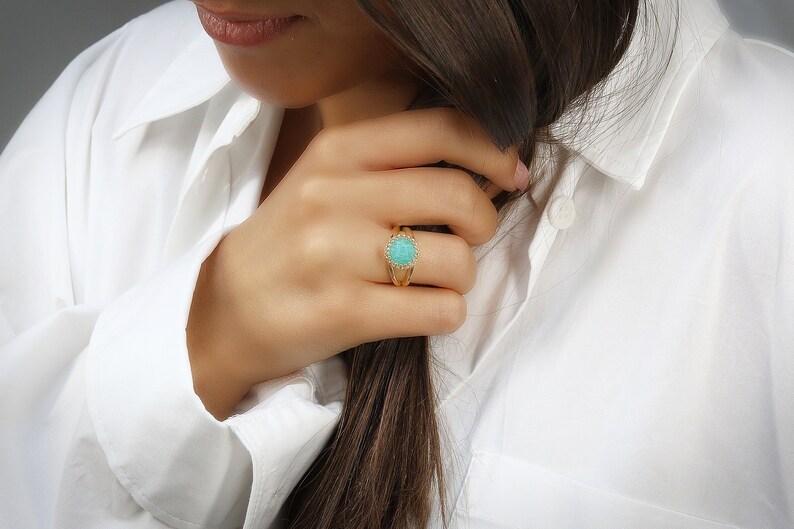 May include: A gold ring featuring a turquoise gemstone surrounded by smaller clear stones.