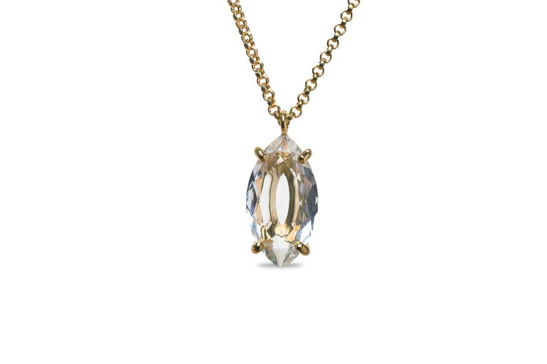 May include: A gold chain necklace with a clear marquise-shaped crystal pendant.