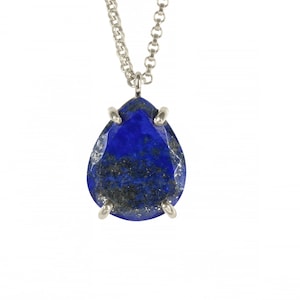 May include: A silver chain necklace with a teardrop-shaped lapis lazuli pendant. The pendant is set in silver and has a dark blue color with gold flecks.