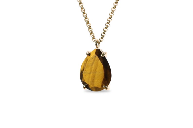 May include: A gold chain necklace with a teardrop-shaped tiger's eye gemstone pendant.
