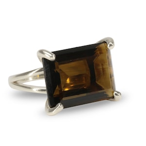 May include: A silver ring with a large, rectangular, brown gemstone.