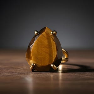 A large, yellow gemstone, possibly a diamond, is displayed on a wooden surface against a dark background.