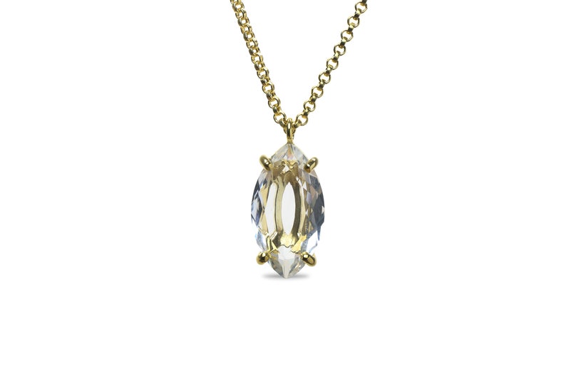 May include: A gold chain necklace with a clear marquise-shaped crystal pendant.