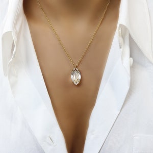May include: A gold chain necklace with a clear, faceted, marquise-shaped pendant.