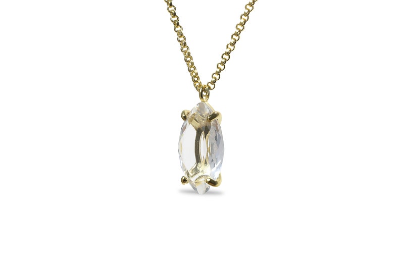 May include: A gold chain necklace with a clear marquise-shaped crystal pendant.