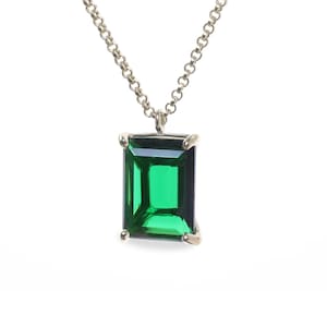 May include: A silver chain necklace with a large emerald green gemstone pendant.
