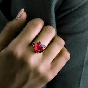 May include: A gold ring with a large, red heart-shaped gemstone.
