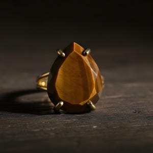 A large, yellowish-brown gemstone, possibly a diamond or amber, is the focal point of the image, resting on a dark surface.