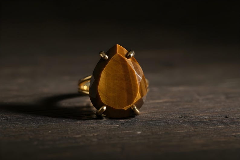A large, yellowish-brown gemstone, possibly a diamond or amber, is the focal point of the image, resting on a dark surface.