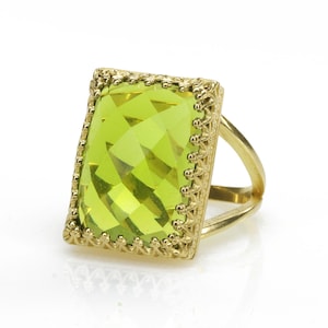 May include: A gold ring with a large, rectangular, green gemstone set in a decorative, gold frame.