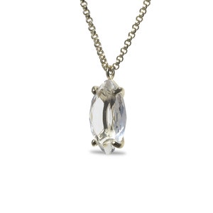 May include: A delicate gold chain necklace with a clear marquise-shaped crystal pendant.