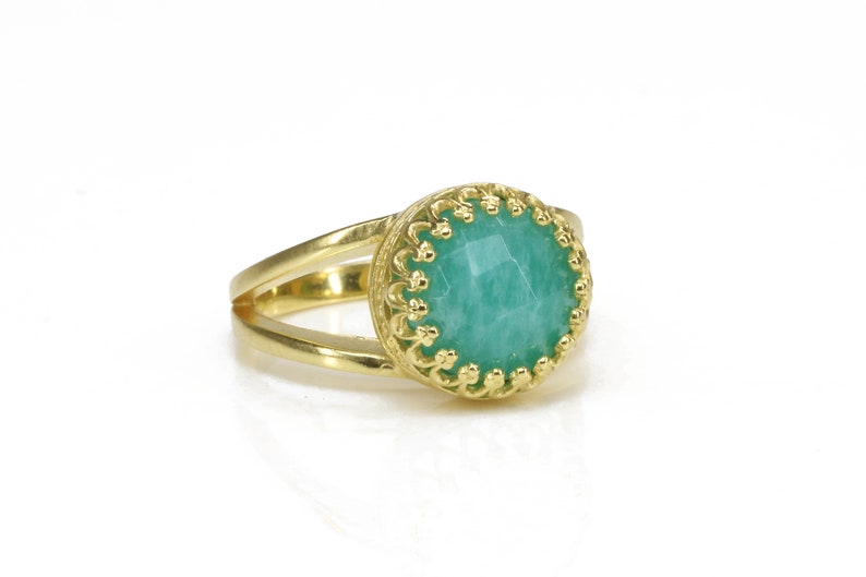 May include: A gold ring with a green gemstone set in a decorative gold bezel. The ring has a double band.