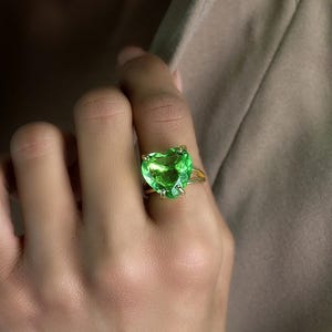 May include: A gold ring with a large, heart-shaped green gemstone.