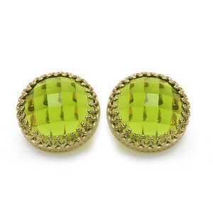 May include: A pair of green glass earrings with gold-toned metal settings. The earrings are round and have a faceted design.
