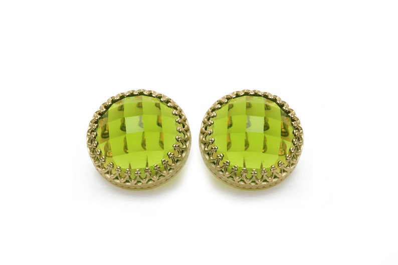 May include: A pair of green glass earrings with gold-toned metal settings. The earrings are round and have a faceted design.