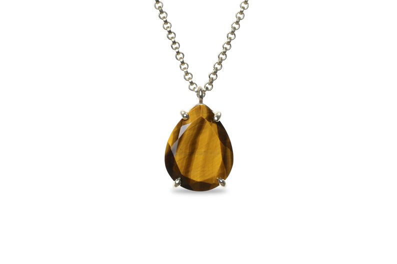 May include: A silver chain necklace with a teardrop-shaped tiger's eye gemstone pendant.