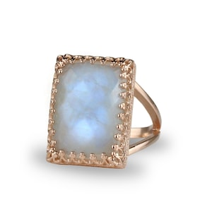 Puede incluir: Un anillo de oro rosa con una piedra de luna rectangular engastada en un delicado diseño de filigrana.