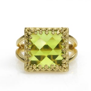 Puede incluir: Un anillo de oro con una piedra preciosa verde cuadrada engastada en un marco decorativo.
