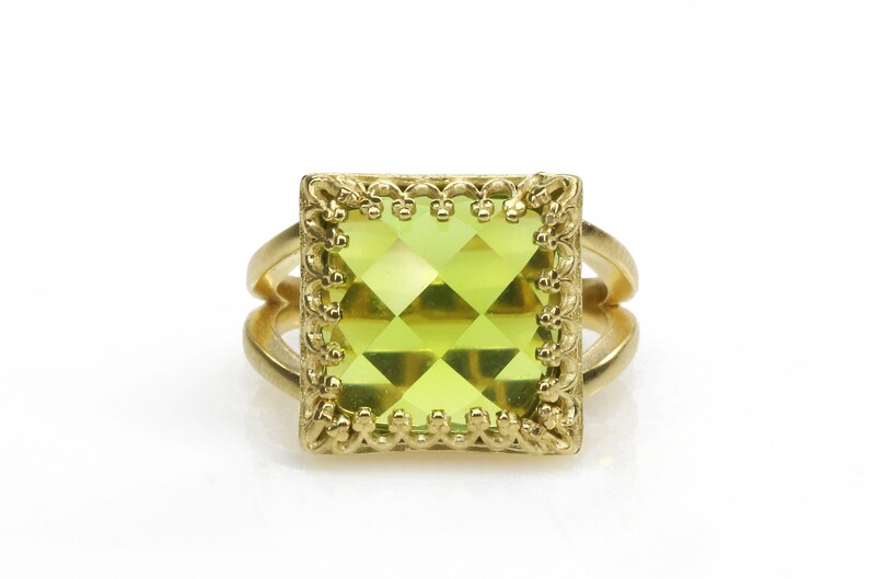 Puede incluir: Un anillo de oro con una piedra preciosa verde cuadrada engastada en un marco decorativo.