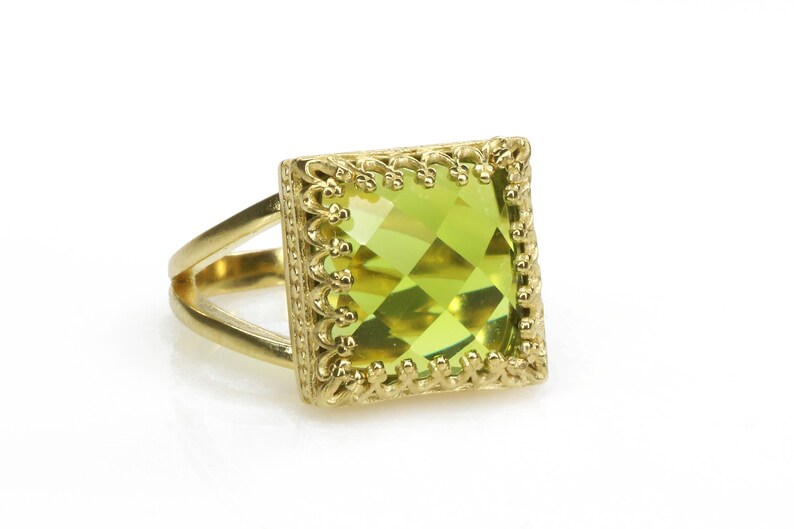 Puede incluir: Un anillo de oro con una piedra preciosa verde cuadrada engastada en un marco de oro decorativo.