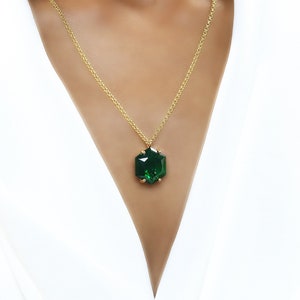 May include: A gold chain necklace with a large, faceted, dark green gemstone pendant.