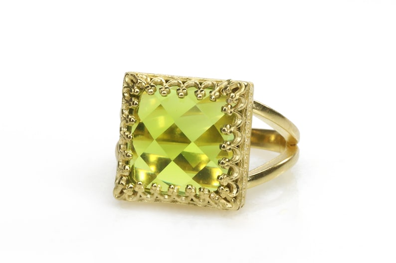 Puede incluir: Un anillo de oro con una gran piedra preciosa verde cuadrada engastada en un marco decorativo ornamentado.