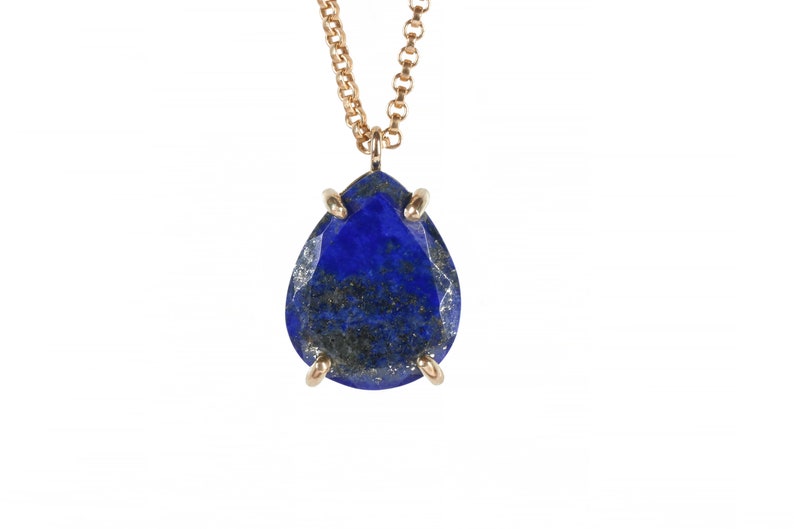 May include: A gold chain necklace with a teardrop-shaped lapis lazuli pendant. The pendant is set in gold and has a faceted design.