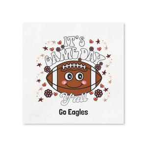 Könnte beinhalten: Quadratischer weißer Druck mit einem Cartoon-Football mit lächelndem Gesicht, umgeben von Sternen, Herzen und Blumen. Der Text lautet "IT'S GAME DAY Y'all Go Eagles" in einer verspielten Schriftart.