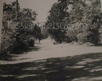 Vtg B&W photo of antique car driving away on road with power line or telephone pole on side.